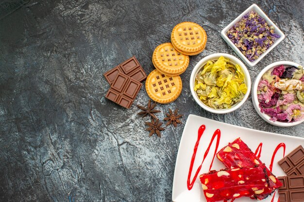 Un plato de chocolate con tazones de flores secas y galletas en el lado derecho del suelo gris