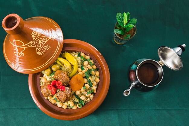 Plato con comida cerca de taza de bebida y tetera