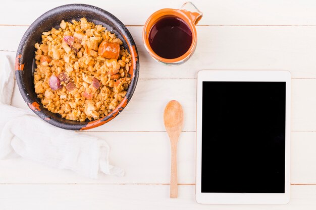 Plato de comida y tableta en la mesa de la cocina