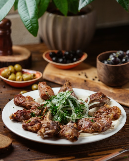 Un plato de costillas de cordero kebab con cebollas y verduras