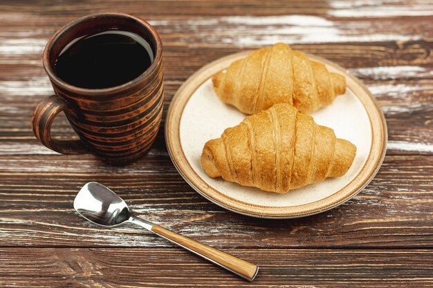 Con el plato con cruasanes y una taza de café sobre la mesa