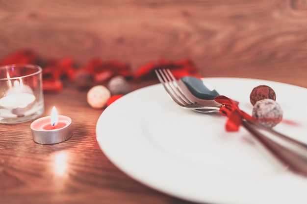 Plato con cubiertos con un lazo y una vela encendida