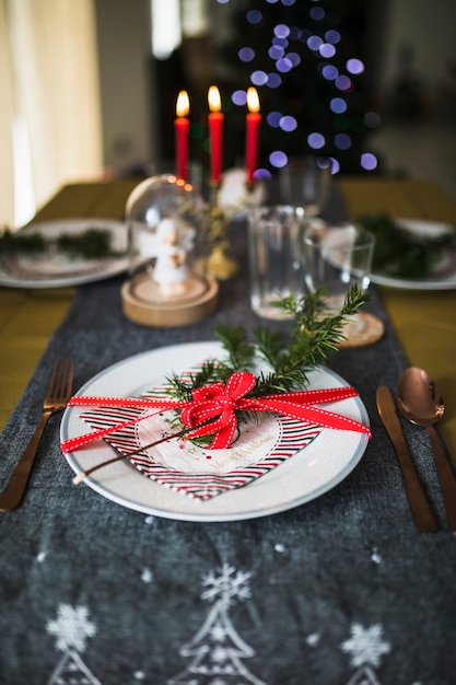 Plato con cubiertos sobre mesa decorada para navidad.