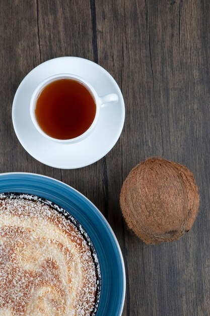 Un plato de delicioso pastel con coco fresco entero colocado sobre una mesa de madera.