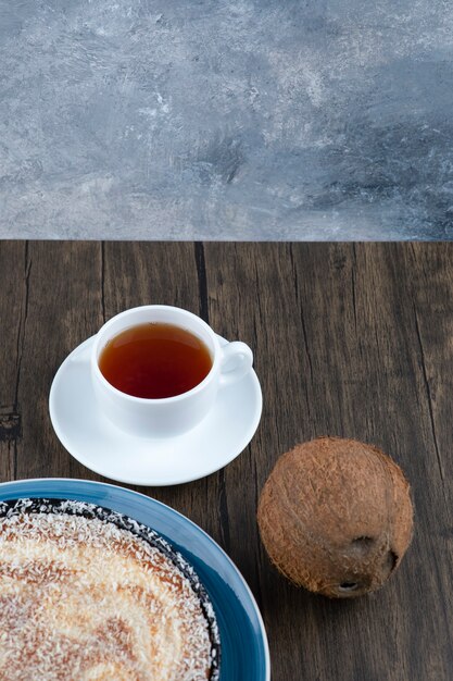 Un plato de delicioso pastel con coco fresco entero colocado sobre una mesa de madera.