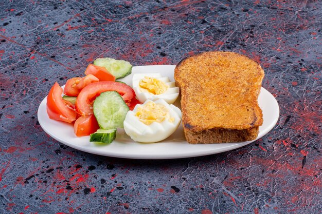 Plato de desayuno con huevos, pepino y rebanadas de pan.