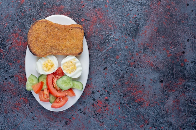 Plato de desayuno con huevos, pepino y rebanadas de pan.