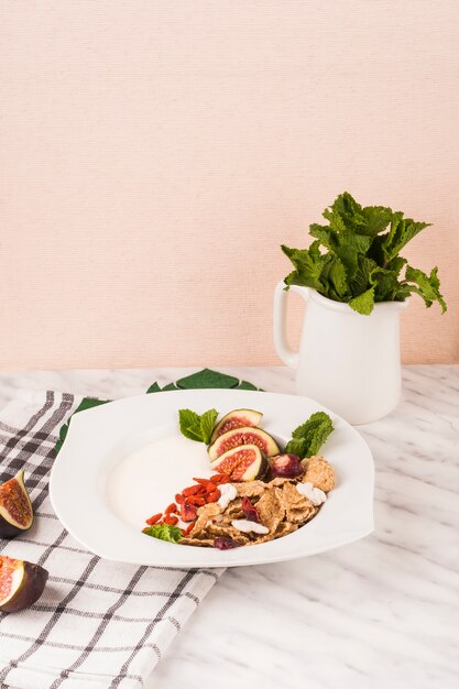 Plato de desayuno con jarra de hojas de menta y servilleta de cocina en mármol blanco