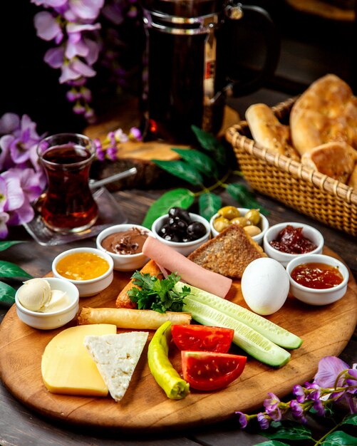 Plato de desayuno turco con queso, verduras, aceitunas, mermeladas, salchichas y envoltura de pan plano