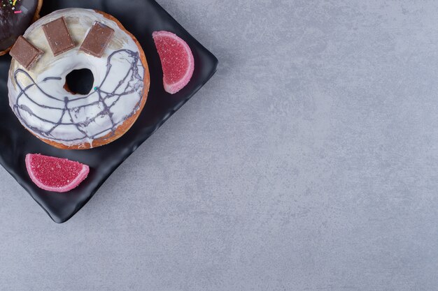 Plato con donuts y mermeladas sobre superficie de mármol