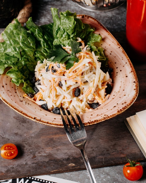 Un plato de ensalada de col con pasas negras y lechuga