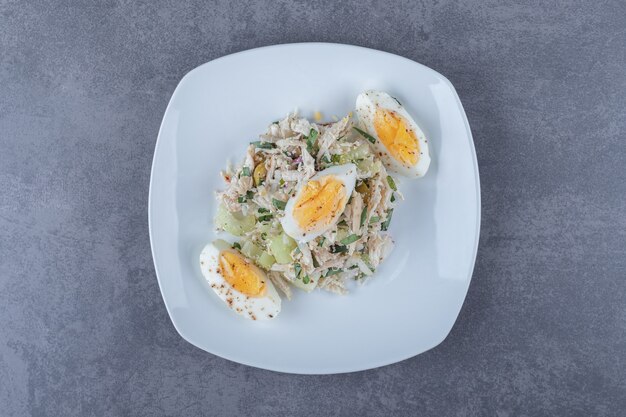 Plato de ensalada con huevo cocido en mesa de piedra.