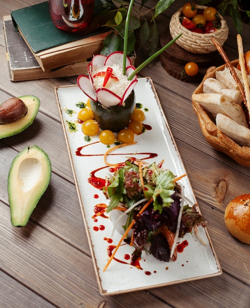 Plato de ensalada de verduras con lechuga, albahaca oscura, aguacate, tomates cherry amarillos