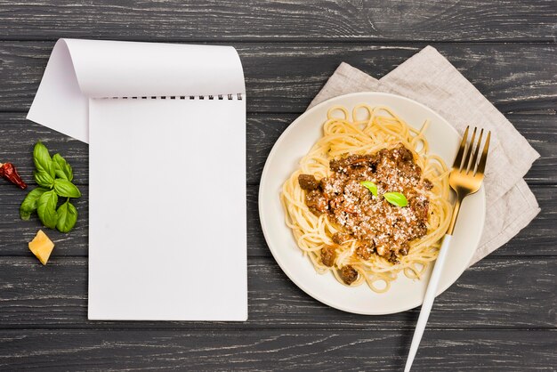 Plato con espagueti a la boloñesa y cuaderno