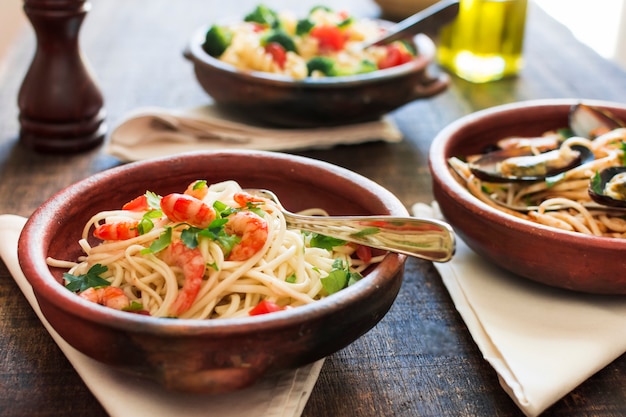 Plato de espaguetis con camarones en mesa de madera
