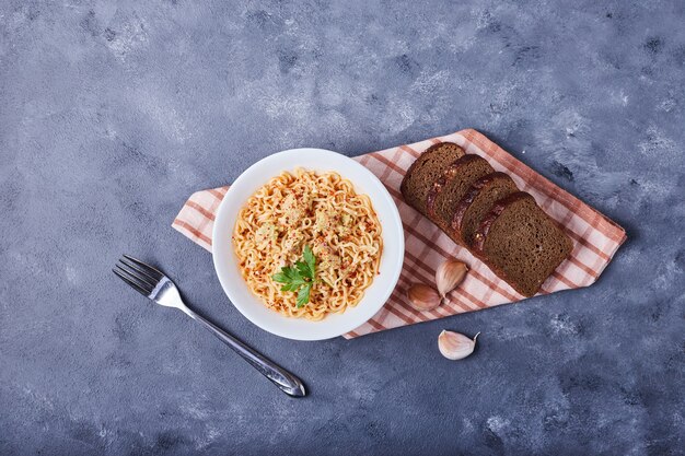 Un plato de espaguetis servido con rebanadas de pan.