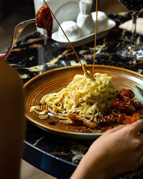 Un plato de fettuccine con camarones en salsa teriyaki