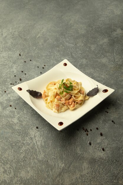 Un plato de fettuccini con pollo en fondo gris liso