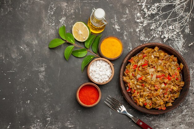 Plato de frijoles y especias cuencos de especias coloridas botella de aceite de limón el plato de judías verdes sobre la mesa oscura