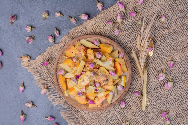 Plato de fruta en rodajas con flores y tela en azul.