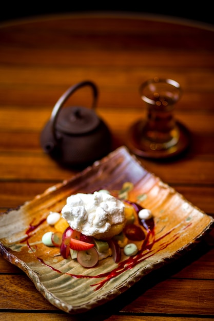 Plato de frutas cubierto con crema y azúcar en polvo