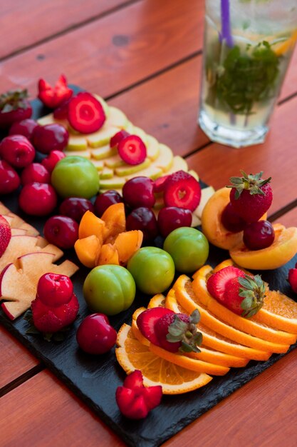 Un plato de frutas exóticas y una copa de mojito.