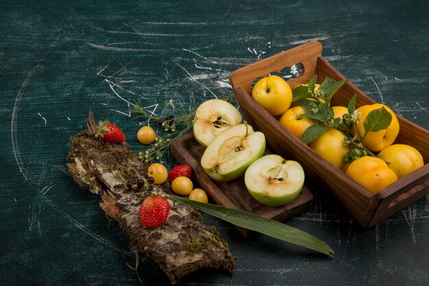 Plato de frutas redondo con peras, manzanas y bayas sobre fondo mate