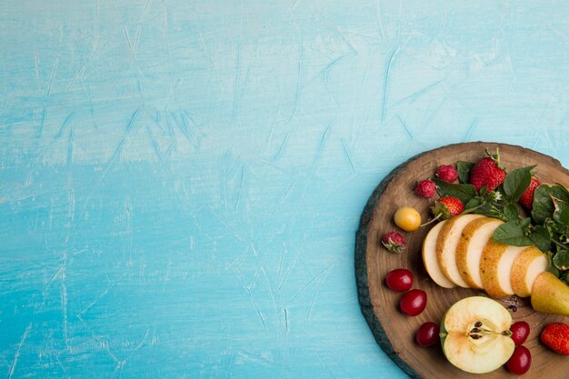 Plato de frutas redondo con peras, manzanas y frutos rojos en la esquina