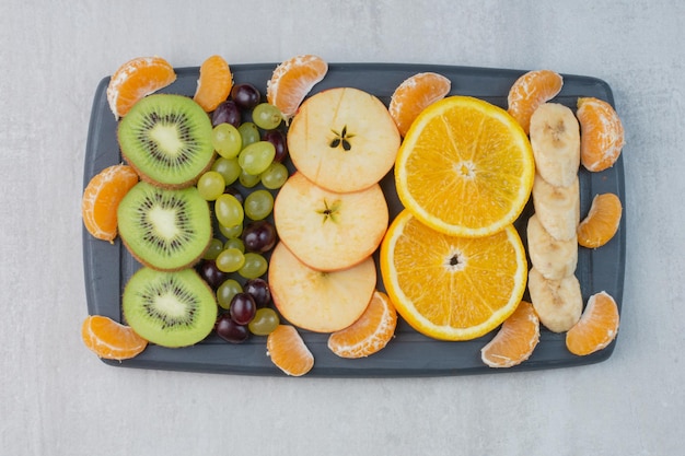 Foto gratuita plato de frutas con rodajas de cítricos, uvas, plátano y kiwi. foto de alta calidad