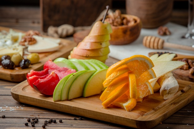 plato de frutas con rodajas de manzana, plátano, ciruela pasa y naranja