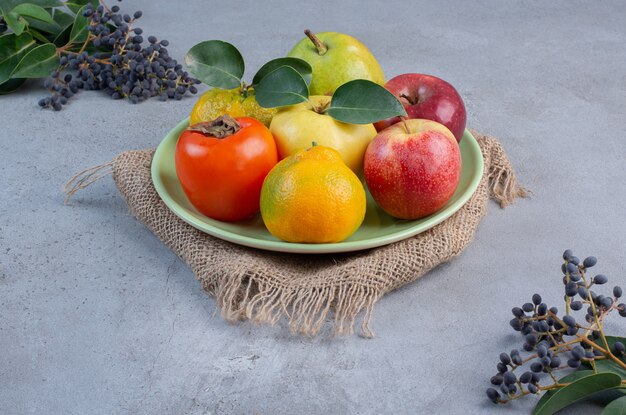 Plato de frutas variadas sobre un trozo de tela sobre fondo de mármol.