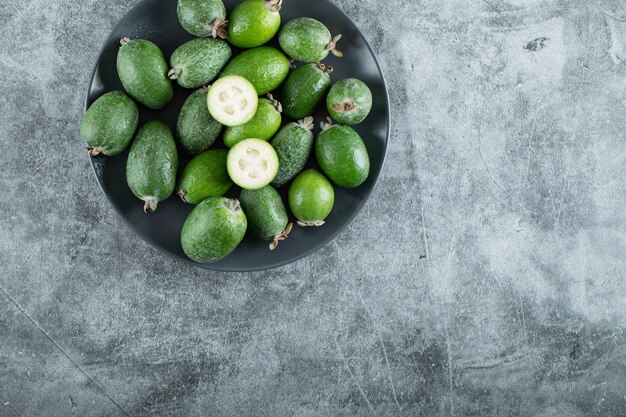 Plato de frutos feijoa sobre fondo de mármol. Foto de alta calidad