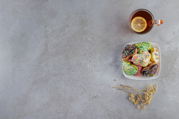 Un plato de galletas en forma de corazón con chispitas y una taza de té caliente