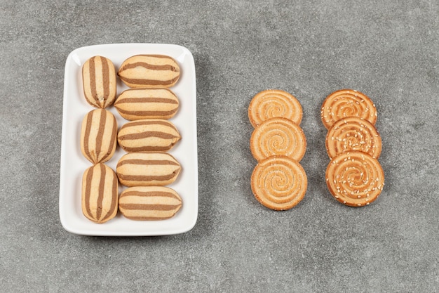 Plato de galletas y galletas de rayas de chocolate en la superficie de mármol