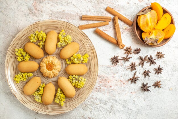 Un plato de galletas y palitos de canela y anís estrellado y un cuenco de palma sobre suelo de mármol