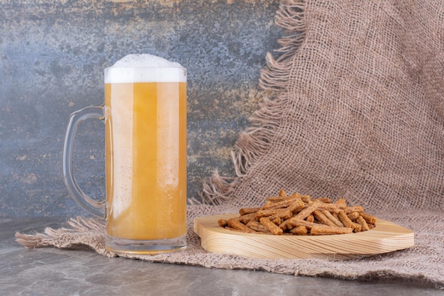 Plato de galletas saladas con cerveza en la mesa de mármol