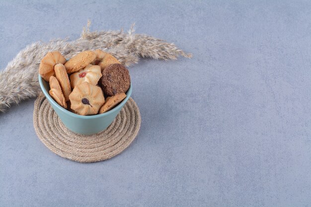 Un plato hondo azul con galletas dulces diferentes sobre una tela de saco.
