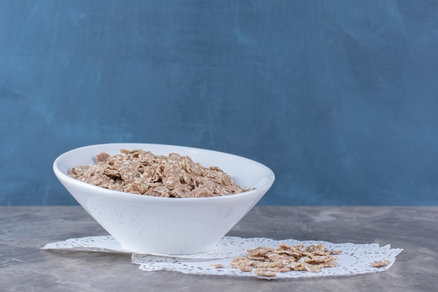 Un plato hondo blanco con copos de maíz saludables en gris.