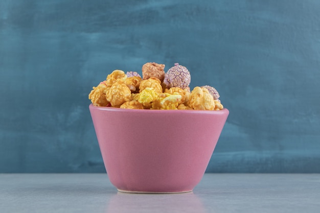 Un plato hondo rosado de dulces palomitas de maíz multicolores.