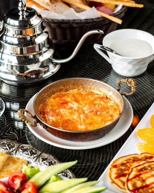 Plato de huevo con tomate servido en sartén de cobre turco