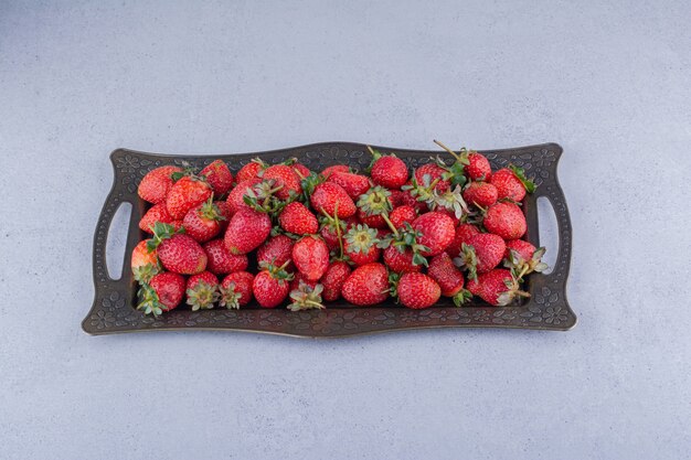 Plato de jugosas fresas sobre fondo de mármol.