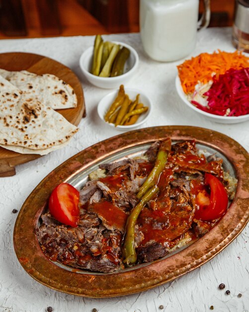 Un plato de kebab de carne cubierto con salsa de tomate