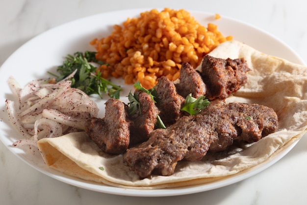 Plato de kebab con pan y cebolla y arroz especiado