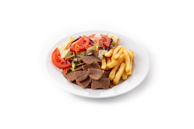 Plato de kebab, verduras y patatas fritas aislado sobre fondo blanco.