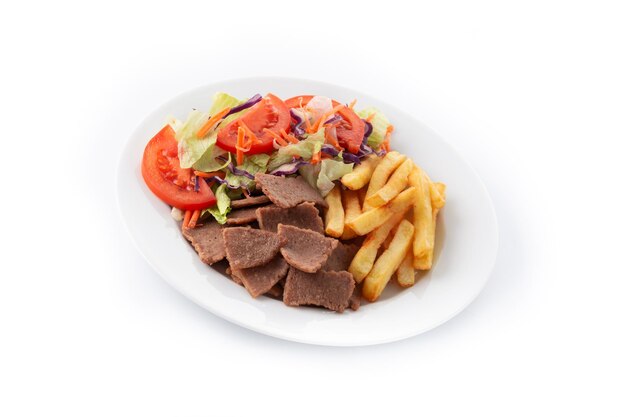 Plato de kebab, verduras y patatas fritas aislado sobre fondo blanco.