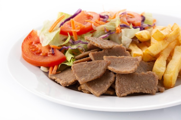 Plato de kebab, verduras y patatas fritas aislado sobre fondo blanco.