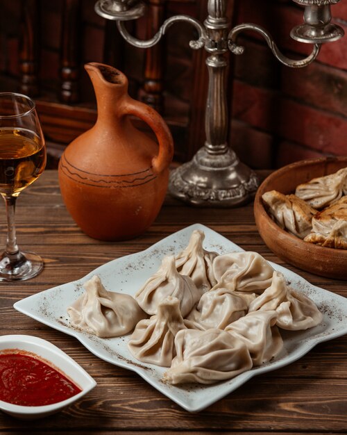 un plato de khinkali georgiano servido con pasta de tomate y vino