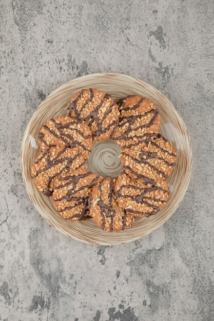 Plato lleno de galletas de avena dulce con sirope de chocolate sobre una piedra.