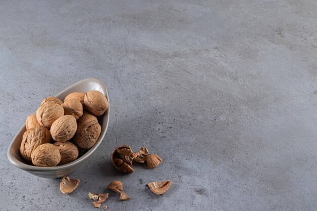 Un plato lleno de nueces saludables colocado sobre fondo de piedra.