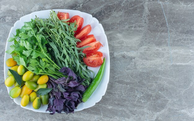 Plato lleno de verduras mixtas, sobre la mesa de mármol.